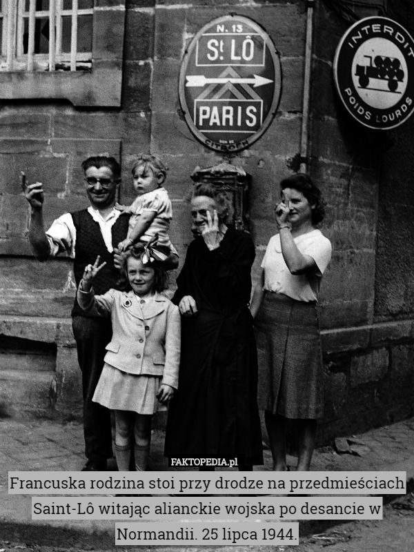 Francuska rodzina stoi przy drodze na przedmieściach Saint-Lô witając alianckie